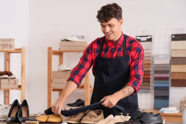 Erkek ayakkabıcı tamircide süet ayakkabıları temizliyor.