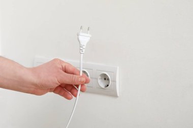 Erkek el prizden çıkıp evdeki ışık duvarına takılıyor, yakın plan.