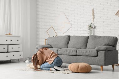 Deprem sırasında oturma odasının ortasında başını koruyan korkmuş genç bir kadın.