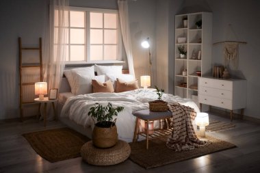 Şık yatak odasının içinde yataklar, raf üniteleri, banklar ve gece lambaları.