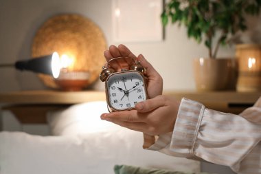 Geceleri yatak odasında çalar saati olan kadın eller.