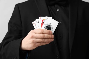 Gri arka planda poker kartları olan genç adam, yakın plan.