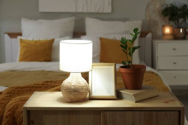 Boş çerçeveli parlayan lamba, kitap ve çiçek akşam yatak odasında klozette.