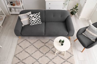 Rahat koltuğu ve gri kanepesi olan aydınlık oturma odasının içinde.