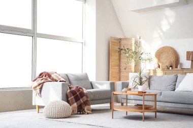 Gri koltukları, kahve masası ve büyük pencereli şık bir oturma odası.