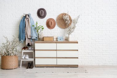 Sallanan giysiler, merdiven ve komodindeki vazolarda açan güzel dallarla oturma odasının içinde.