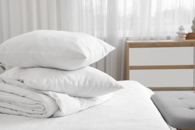 Katlanmış battaniyeli rahat yatak ve şık yatak odasında yumuşak yastıklar, yakın çekim.