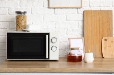 Mutfaktaki masada, mikrodalganın yanında bir kavanoz şekerli çaydanlık.