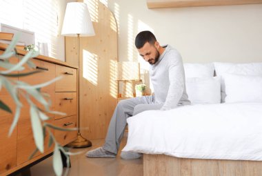 Evde sırt ağrısı çeken genç bir adam.