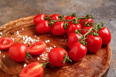 Koyu arkaplanda taze kiraz domatesli ahşap tabak.