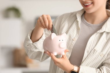 Genç kadın kumbara evde, closeup para koyarak