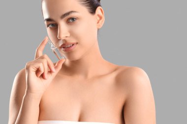 Gri arka planda ampul tutan güzel genç bir kadın.