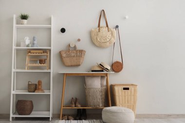 Salonun içinde kahve masası, raf ünitesi ve hasır çantalar var.