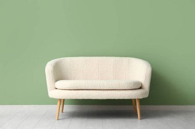 Yeşil duvarın yanındaki rahat beyaz kanepe