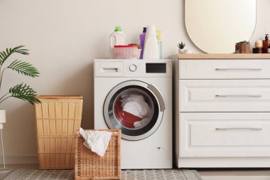 Modern çamaşır makinesi, çekmece sandığı ve beyaz duvardaki ayna.