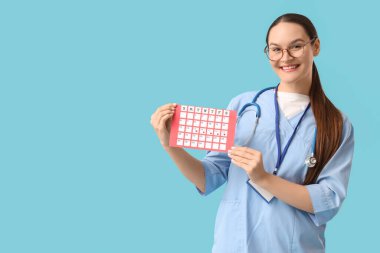 Mavi arka planda adet takvimi olan kadın doktor.