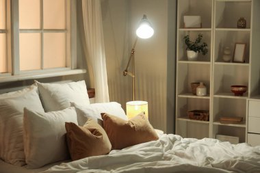 Şık bir yatak odası, yatak odası, raflar ve geceleri parlayan lambalar.