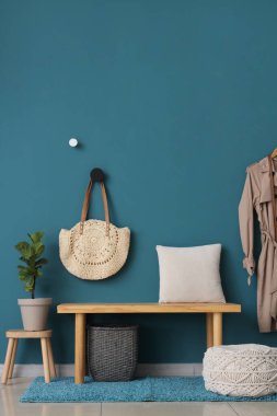 Yastıklı bank, çiçekli ve mavi duvarda asılı çanta.