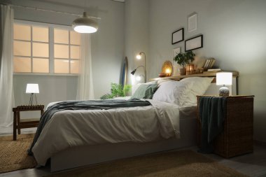 Şık bir yatak odası, yatak odası, sörf tahtası, parlayan lambalar ve akşamları raflarda ev dekorasyonu.