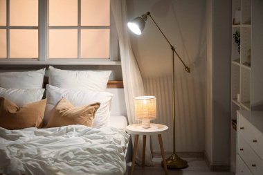 Şık bir yatak odası, yatak odası, raflar ve geceleri parlayan lambalar.