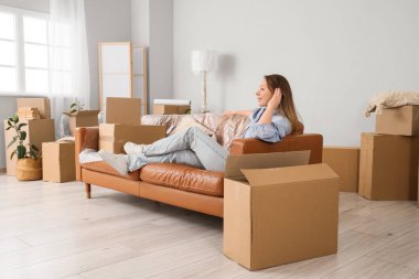 Genç bir kadın yeni dairesinde kanepede yatıyor.