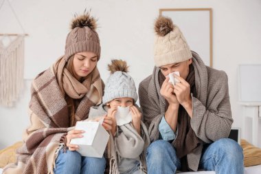 Hasta küçük kız ve ailesi, yatak odasında hapşıran sıcak ekose elbiseleriyle.