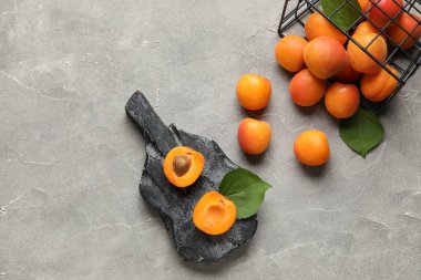 Gri arka planda taze kayısıları olan sepet ve yemek.