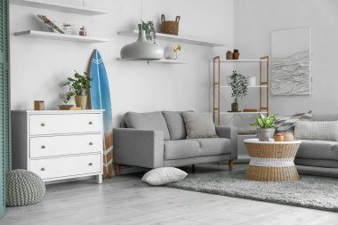 Sörf tahtası, rafları ve kanepeleri olan bir oturma odası.