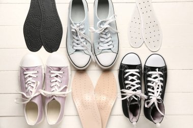 Açık ahşap zemin üzerinde farklı ayakkabı ve ortopedik tabanlı kompozisyon