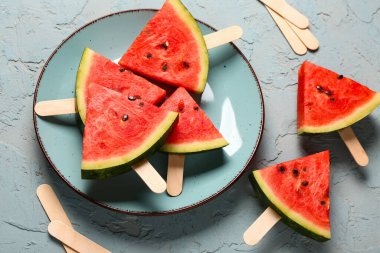 Mavi arka planda tatlı karpuz çubukları olan bir tabak.