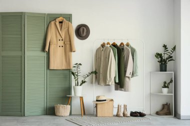 Giysi askısı, katlama ekranı ve raf ünitesi olan odanın içi