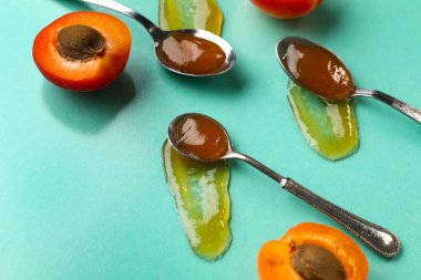 Yeşil arka planda tatlı kayısı reçelli metal kaşıklar