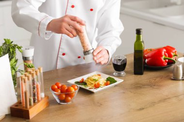 Erkek aşçı mutfaktaki masada tuzlu makarna yiyor, yakın plan.