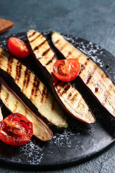Koyu arkaplanda lezzetli ızgara patlıcan ve domates.