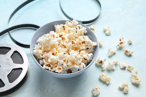 Чаша с вкусным попкорном и кинокатушкой на синем фоне