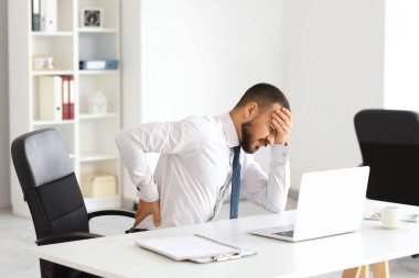 Ofiste sırt ağrısı çeken genç bir işadamı.