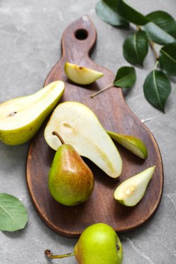 Gri masa üzerinde olgun armutlar olan ahşap tahta, yakın plan.