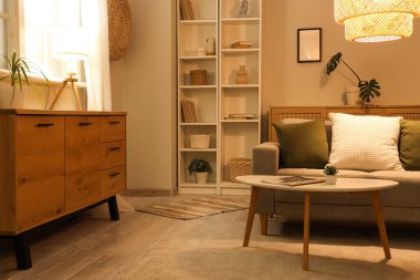 Gri kanepesi, kahve masası ve gece lambasıyla şık bir oturma odası.