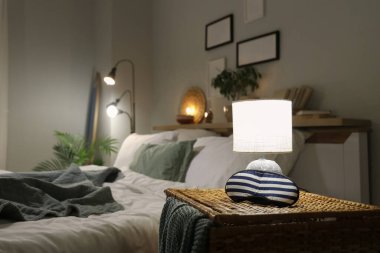 Gece yatak odasının yanındaki hasır masada uyku maskesiyle parlayan lamba.