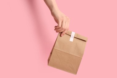 Pembe arka planda kese kağıdı olan bir kadın. Yemek dağıtım servisi.