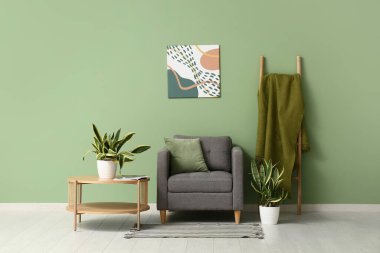 Sansevieria bitkileri, koltuk, merdiven ve odanın içindeki yeşil duvarın yanındaki masa.