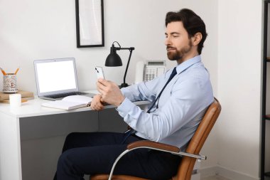 Ofiste cep telefonuyla çalışan yakışıklı bir işadamı.