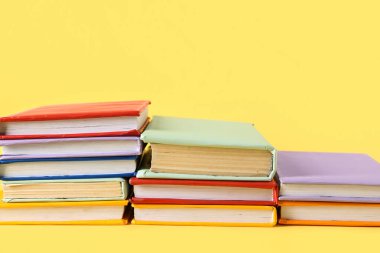 Sarı arkaplan üzerine renkli kitap yığınları