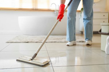 Banyoda paspas yapan genç bir kadın.