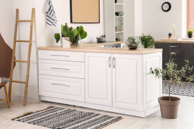 Beyaz tezgahları ve halıları olan aydınlık mutfağın içi.