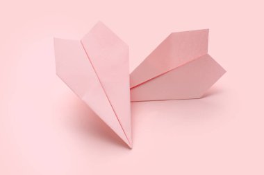 Pembe arka planda kağıt uçaklar