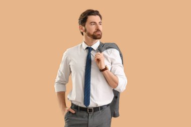 Bej arka planda ceketi olan resmi giysili yakışıklı bir genç.