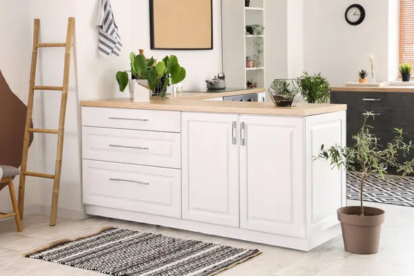 Beyaz tezgahları ve halıları olan aydınlık mutfağın içi.