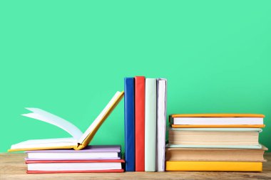Birçok renkli kitap yeşil arka plana karşı ahşap masa üzerinde