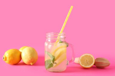 Mason kavanozu taze limonata, nane ve pembe arka planda limon.